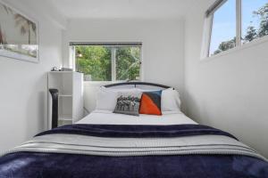 a bedroom with a large bed with two windows at Charming Guest House in the Bays in Auckland