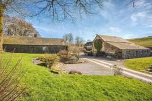 a large stone building in a grassy field next to a house at Sheldon Cottage in Buxton