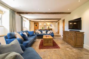 ein Wohnzimmer mit blauen Sofas und einem Fernseher in der Unterkunft Atherstone Farm Cottage in Stocklinch