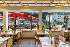 a restaurant with tables and chairs and red umbrellas at Hostel Casa Franco in St. Moritz