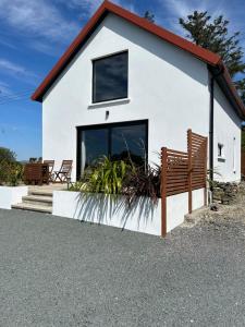 a small white house with two benches in front at The ring fort lodge in Glenties