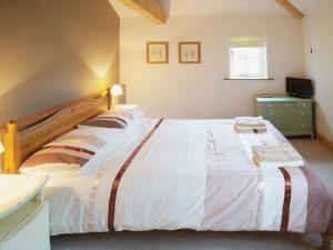 ein Schlafzimmer mit einem großen weißen Bett mit einem hölzernen Kopfteil in der Unterkunft Brimble Cottage in Axminster + 6 Fotos