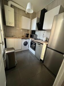 a kitchen with white cabinets and a washer at Appartement in Montreuil