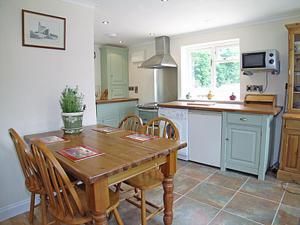 eine Küche mit einem Holztisch und einigen Stühlen in der Unterkunft Chapel Cottage in Kentisbury