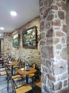 a stone walled restaurant with wooden tables and chairs at A Vianda in Muros