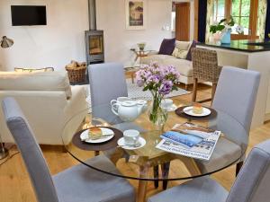 Una sala de estar con una mesa de cristal y sillas. en The Wagon House, en Luxulyan