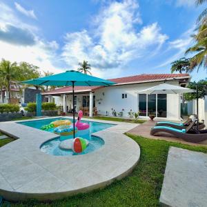 einen Pool mit Sonnenschirm und Stühlen und ein Haus in der Unterkunft Bungalow en La Playa- Amatecampo Villas in La Esmeralda