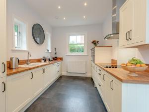 a kitchen with white cabinets and a bowl of fruit on the counter at Langford Villa in Filey