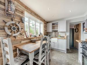 a kitchen with a wooden wall and a wooden table and chairs at Nelson Cottage in Tenby