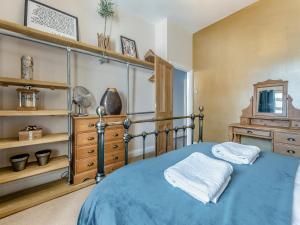 a bedroom with a blue bed and a dresser at Nelson Cottage in Tenby +15 photos