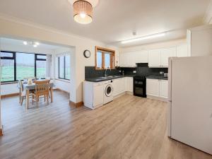 una cucina con armadi bianchi e una sala da pranzo con tavolo di Shellhill Cottage a Kirkcudbright