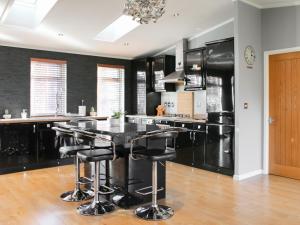 una cocina con encimeras negras y una isla negra con taburetes. en Stag Lodge, en Auchterarder