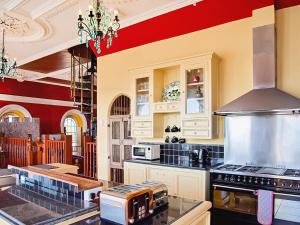 a kitchen with white cabinets and a red wall at The Auction House in Criccieth +27 photos