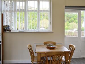 a wooden table in a kitchen with two windows at Station House - Hw7742 in Glyn-Dyfrdwy