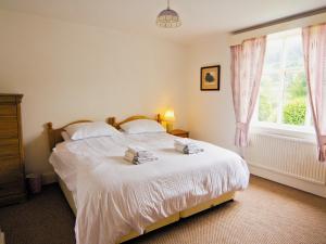 a bedroom with a bed with white sheets and a window at Station House - Hw7742 in Glyn-Dyfrdwy +4 photos