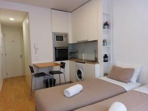 a bedroom with two beds and a kitchen with a table at São Marcos Apartaments in Braga