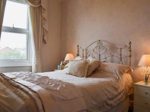 1 cama en un dormitorio con 2 lámparas y una ventana en Ash Villas, en Southport