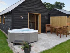 a black building with a hot tub and a table at Saddlers Cottage in Alkham