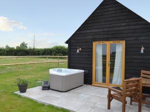 a hot tub sitting on a patio next to a house at Saddlers Cottage in Alkham +7 photos