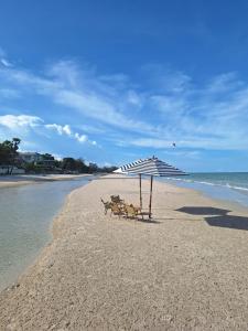 two chairs under an umbrella on a beach at Mango Paradise, in der Nähe des Black Mountain Golf Clubs in Hua Hin
