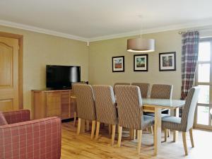 a dining room with a table and chairs and a television at Lochnagar Lodge in Aviemore