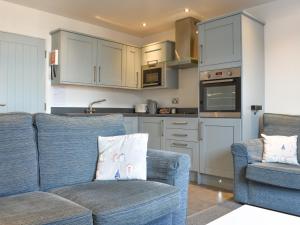 a living room with two blue chairs and a kitchen at Sea Blue Cottage in Scarborough