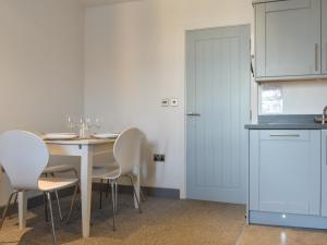 a kitchen with a table with white chairs and a door at Sea Blue Cottage in Scarborough