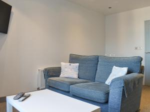a living room with a blue couch and a white table at Sea Blue Cottage in Scarborough