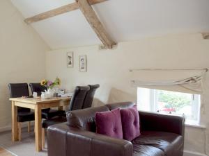 a living room with a leather couch and a table at The Hayloft - Uk6715 in Lydstep