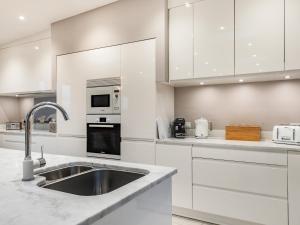 a kitchen with white cabinets and a sink at Primrose Cottage in Holyhead