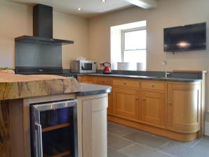 een keuken met houten kasten en een kookplaat met oven bij Souterstead in Torver +19 foto's