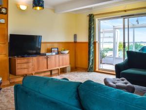 a living room with a blue couch and a flat screen tv at The Boat House in Canterbury