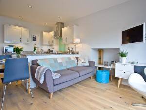 Una sala de estar con un sofá y una cocina. en Curlew 4 - The Cove, en Brixham