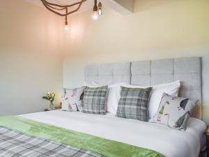 Un dormitorio con una cama con almohadas verdes y blancas. en Shelduck Cottage, en Holmfirth 22 fotos más