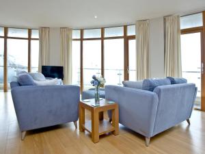 Una sala de estar con dos sofás azules y una mesa. en Pebbles, Horizon View, en Westward Ho