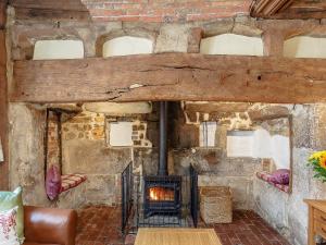 a stone fireplace in a room with a brick wall at Pollard Cottage in Lingfield