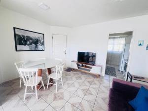 a living room with a table and chairs and a tv at Apê Brisa do Mar in Pontal do Paraná