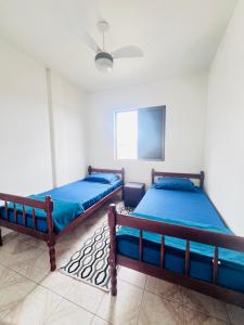 two beds in a room with a ceiling fan at Apê Brisa do Mar in Pontal do Paraná