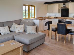 a living room with a couch and a kitchen at Horseshoe Cottage in Alkham