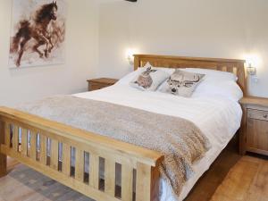 a bedroom with a wooden bed with white sheets and pillows at Horseshoe Cottage in Alkham +8 photos