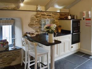 Una cocina con una mesa con un jarrón de flores encima. en Driftwood, en Newquay