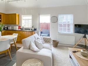 a living room with a white couch and a kitchen at The Guards Quarters - Uk47594 in Silloth