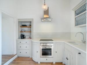 eine weiße Küche mit Herd und Spüle in der Unterkunft The Reading Room in Askham