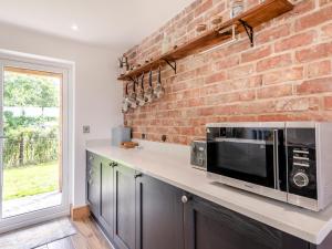 cocina con microondas y pared de ladrillo en Heron's Den - Uk44529, en Horncastle 14 fotos más
