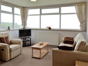 un soggiorno con 2 sedie e una TV di Mill Shore Cottage - 26817 a Pennan