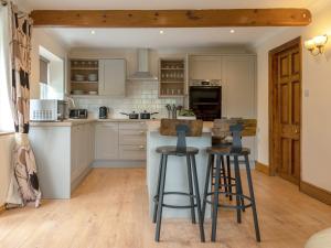 una cucina con mobili bianchi e sgabelli da bar di Riverside Cottage-Uk41439 a Brandon