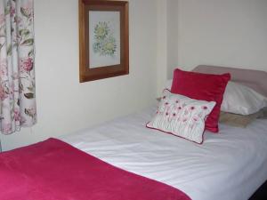 un letto con due cuscini rossi e bianchi di The Granary a Burscough Altre 9 foto