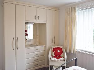 a bedroom with a dresser and a chair with a red pillow at Polperro in Keswick +6 photos