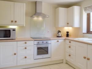 a kitchen with white cabinets and a microwave at Woodpecker Cottage - Ukc3412 in Bolton by Bowland