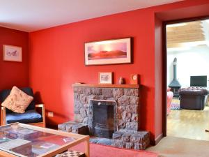 a red living room with a stone fireplace at The Old Smiddy in Poolewe